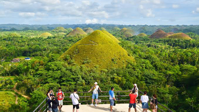 A group of tourists enjoying the breathtaking view of the Chocolate Hills, capturing memories against the backdrop of this natural wonder
