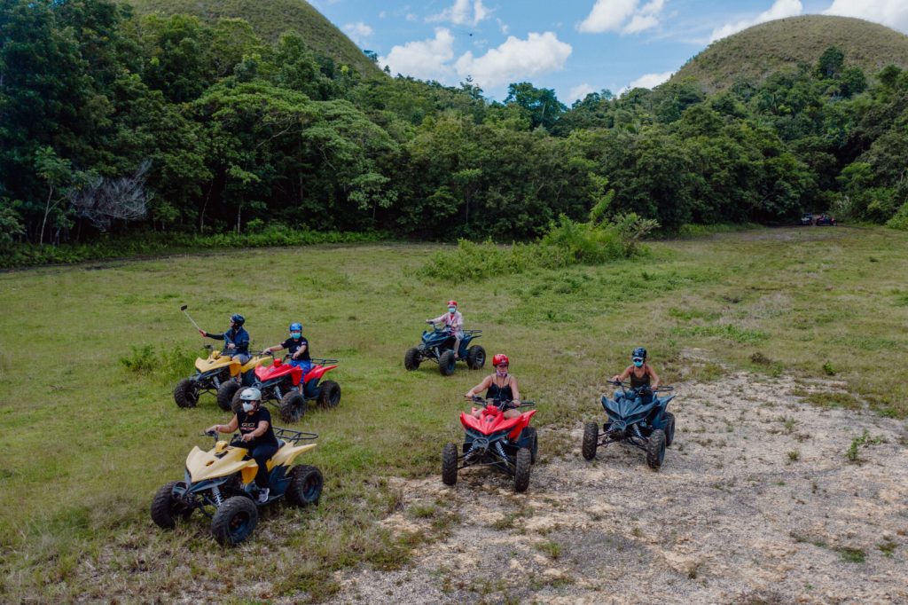 A group of excited riders on ATVs, navigating through a rugged terrain