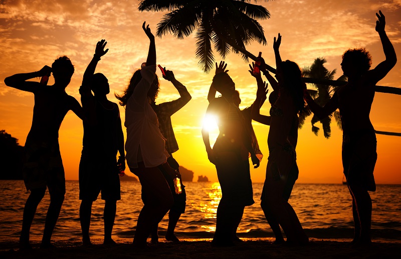 Silhouetted figures of a group of people standing together against a vibrant sunset
