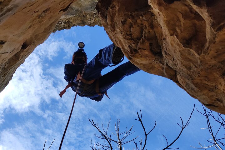 A man engaged in rappelling, skillfully navigating the descent with a beautiful landscape in the background.