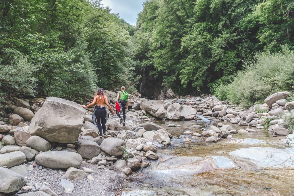 Excited tourists hiking along a river, with backpacks and gear